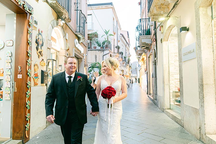 Bride and groom walking hand in hand through Taormina’s historic streets during their romantic wedding photoshoot in Sicily.
