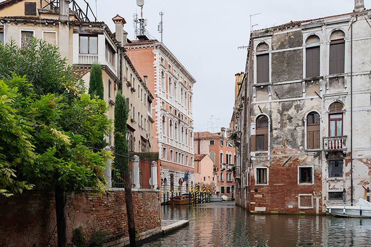 Quiet Venetian canal lined with historic buildings and lush greenery