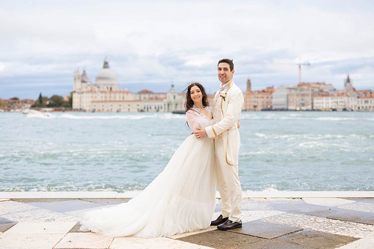 Bride and groom standing together with the Venetian lagoon as their backdrop