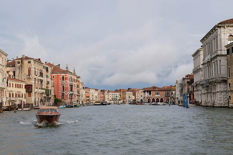 Wooden water taxi entering the Grand Canal surrounded by Venetian architecture