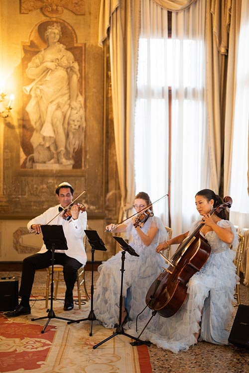 String trio performing during the interfaith wedding ceremony in a frescoed Venetian hall