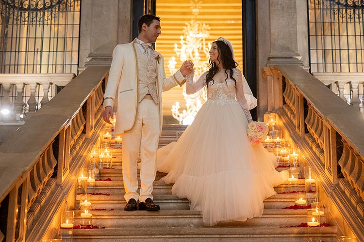 Bride and groom walking down candlelit stairs inside an ancient Venetian palace after the ceremony