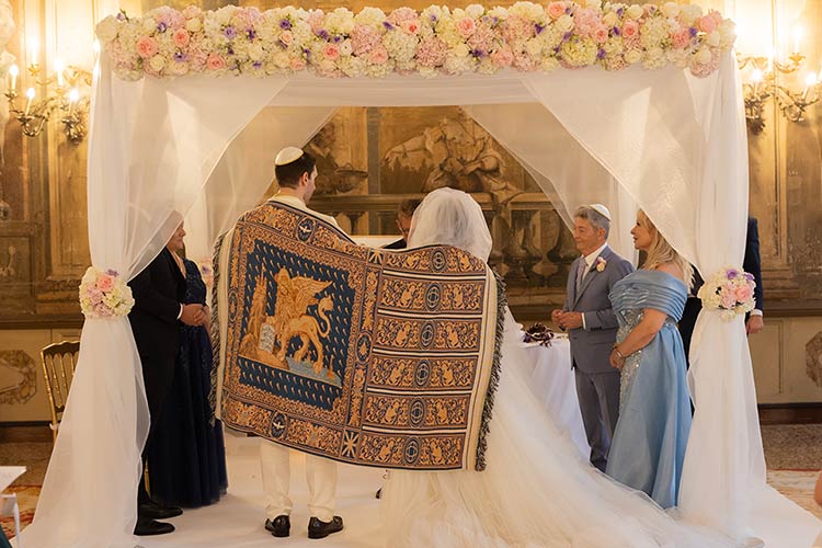 Bride and groom standing beneath the chuppah during their interfaith wedding ceremony in Venice