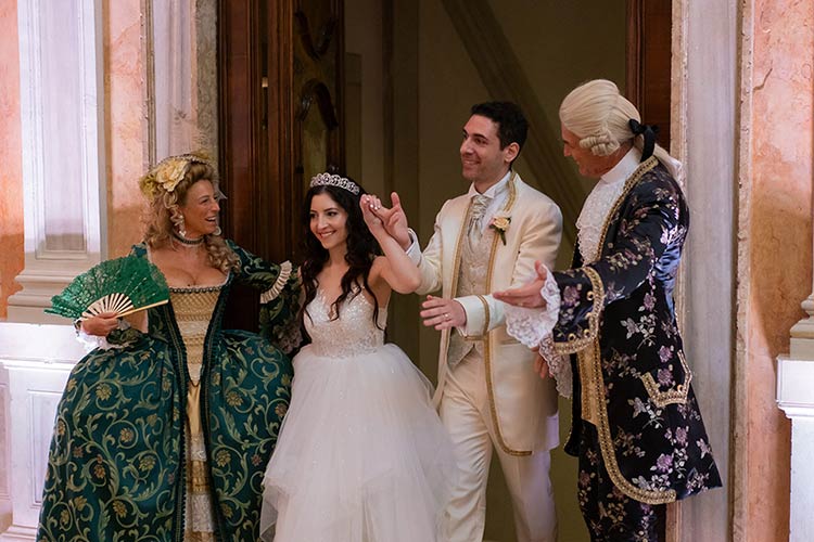 Elegant wedding dinner setup inside a historic Venetian palace with floral centerpieces and warm lighting.