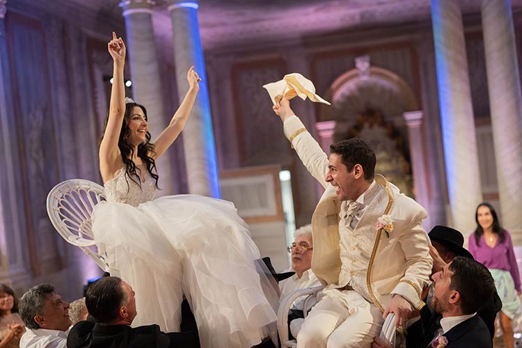 Bride and groom lifted on chairs during the traditional Jewish Hora dance at their Venice wedding.