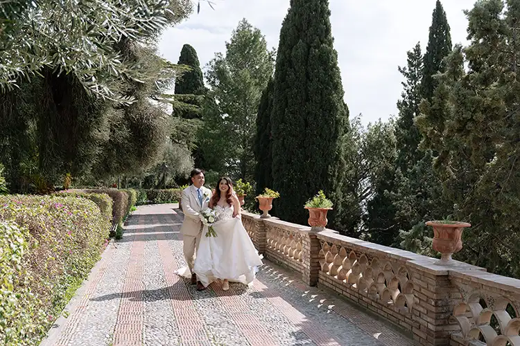 Romantic walk of the bride and groom in a Sicilian garden during a winter wedding in Taormina