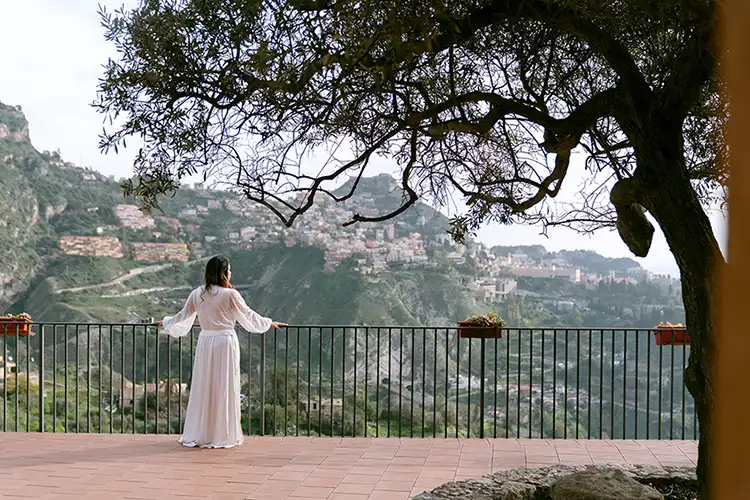 Bride admiring the view of Taormina from a private villa terrace on her winter wedding day