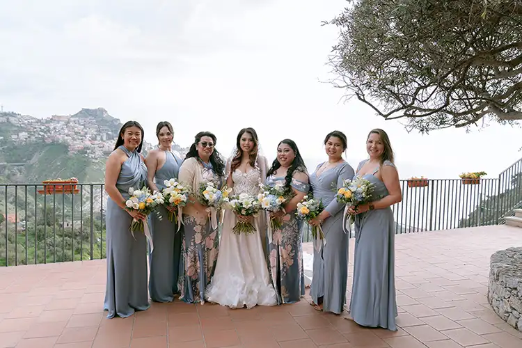 Bride and bridesmaids with winter wedding bouquets overlooking Taormina, Sicily