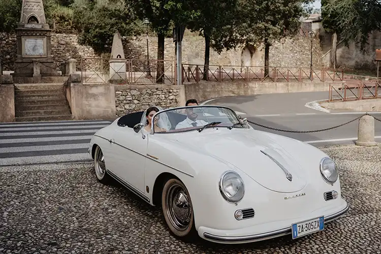 Bride arriving at the Church of the Nativity of Mary in a vintage Porsche in Garlenda