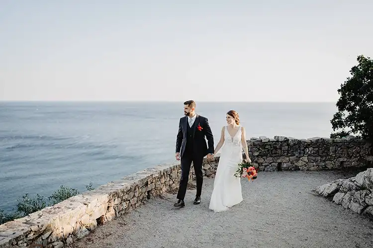Newlyweds walking along a scenic seaside path overlooking the Mediterranean on the Italian Riviera