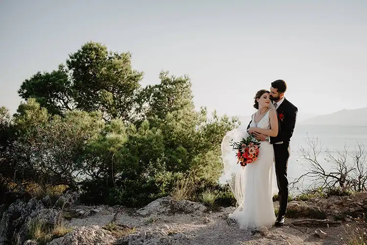 Romantic portrait of the bride and groom surrounded by Mediterranean vegetation overlooking the sea