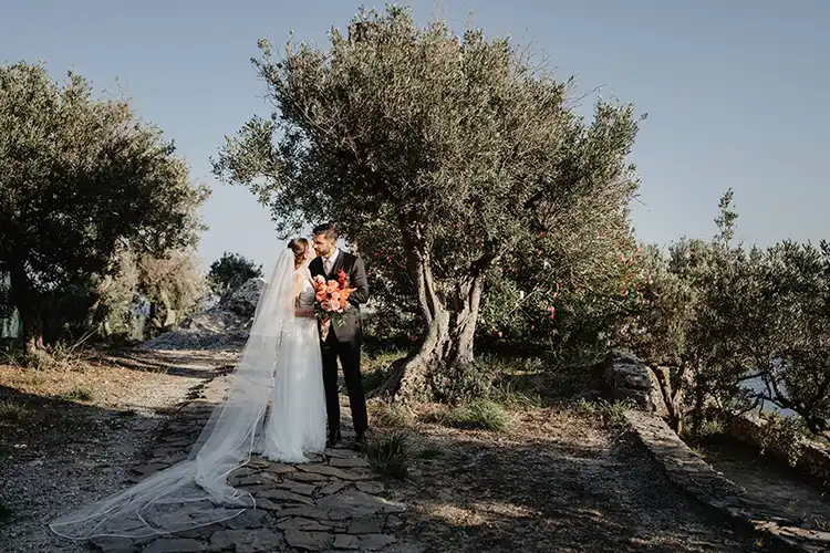 Bride and groom embracing beneath ancient olive trees during their Italian Riviera wedding portraits