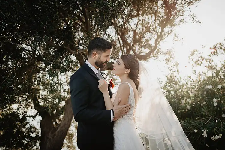 Bride and groom embracing beneath Mediterranean trees overlooking the Italian Riviera