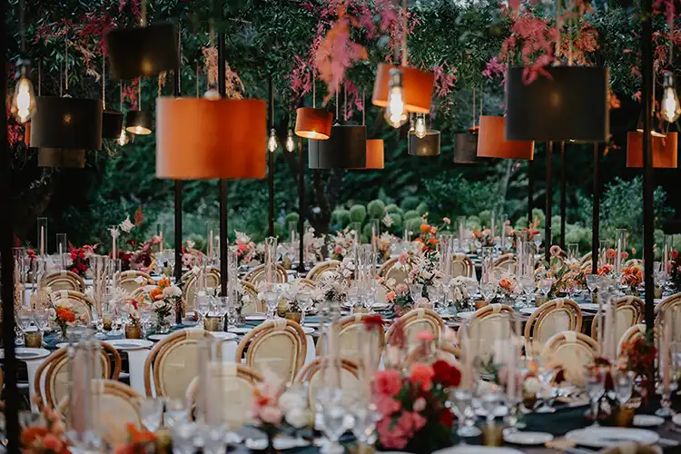 Suspended floral installations above long imperial tables at an outdoor wedding reception in Liguria
