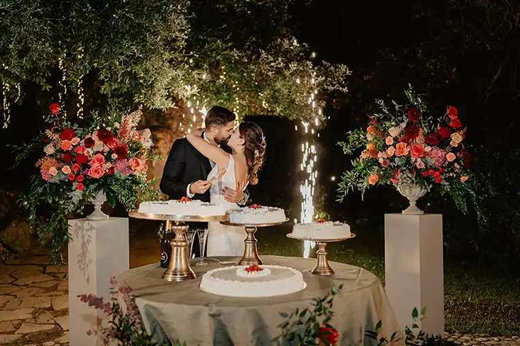 Bride and groom cutting their wedding cake beneath sparkling lights during an evening reception in Liguria